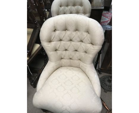 A pair of modern Victorian style chairs with button back seats .