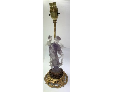 A purple carved rock crystal figure on a gilt brass lamp base.