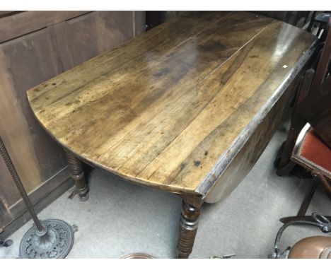 An Early Victorian Vernacular drop leaf dining table with a planked top possible indigenous fruitwood on ring turned legs len