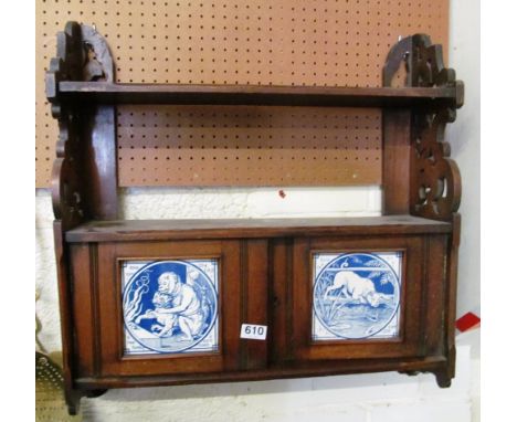 An Edwardian two tier wall shelf with tile inset cupboard of monkey with cat and a dog looking in pond