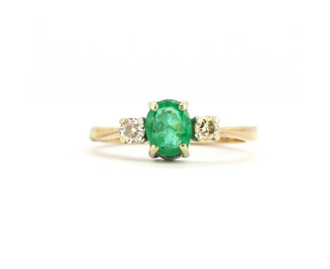 A 9ct yellow gold ring set with an oval cut emerald and diamonds, (I).