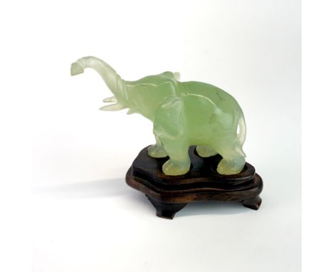 A Chinese carved jade elephant on a carved wooden stand, overall H. 8cm.