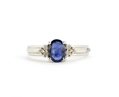 A 14ct white gold ring set with an oval cut sapphire and brilliant cut diamonds, (M.5).
