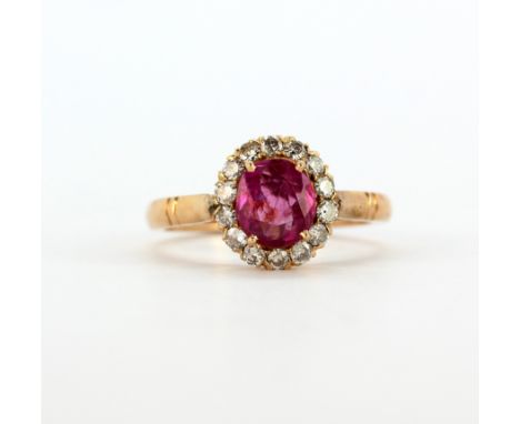 A rose metal (tested high carat gold) cluster ring set with an oval cut pink sapphire surrounded by diamonds, (L). Weight - 3