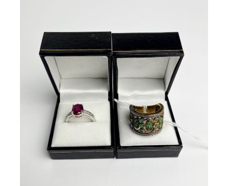 A silver and ruby ring together with a silver and emerald ring.