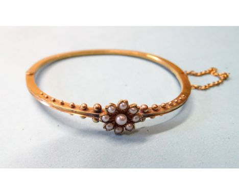 A Victorian gold hinged bangle with flower head pearl cluster and graduated bead decoration, internal dimensions 5.4 x 4.6cm,