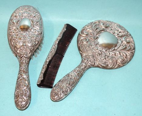 A modern silver-backed hand mirror, clothes brush and comb with embossed decoration, Birmingham 1962, (3). 