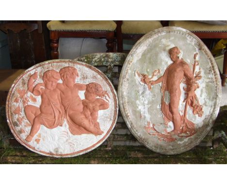 Two cast concrete oval wall plaques decorated with classical figures and putti, 80cm high x 66cm wide and 70cm high x 68cm wi