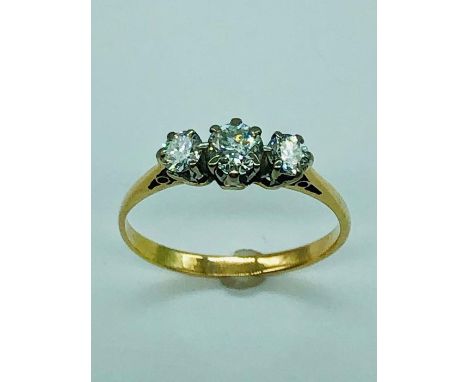 A three stone diamond ring on yellow gold.