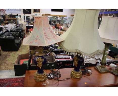 A pair of ornate ceramic and gilt metal lamp base, dark blue ground raised globe shape, mounted on a gilt metal stand with sh
