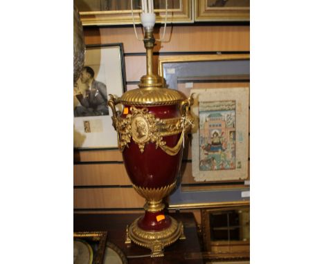 A large baluster shape lamp base, maroon ground with applied gilt fittings, raised on a gilt metal plinth, in the Roman reviv