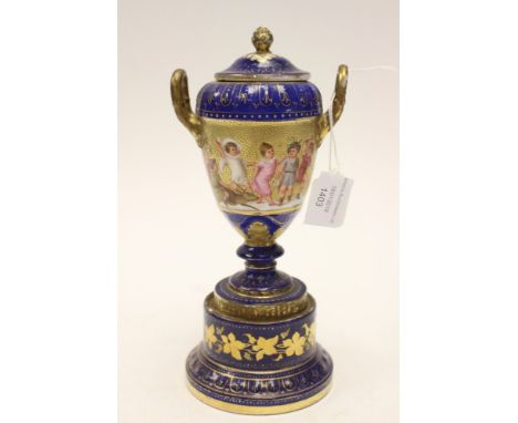 A Vienna porcelain urn and cover, raised on a porcelain plinth children playing and a deer, dark blue ground with gilded deco