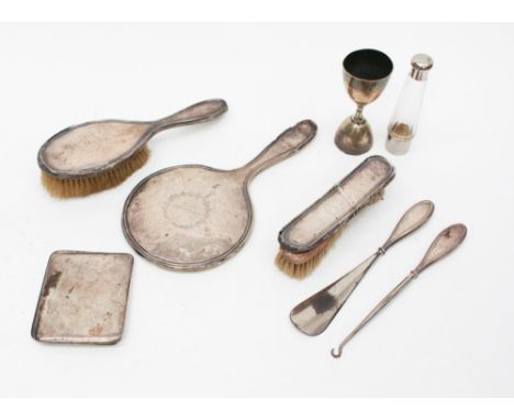 A silver cigarette case with engraving to the inside, a silver backed mirror and brushes, shoe horn, button hook, along with 