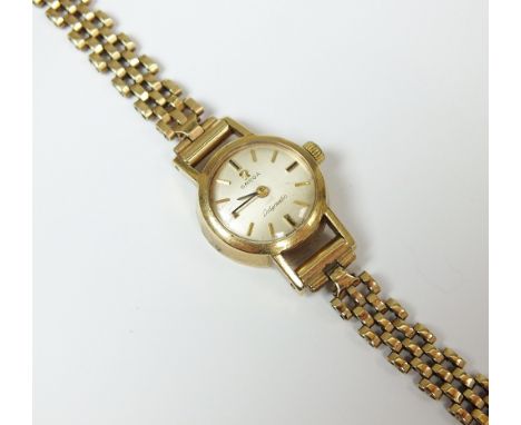 A Lady's 9ct gold Omega Ladymatic watch, the silvered dial with batons, manual wind, with attached 9ct gold 3 bar gate bracel