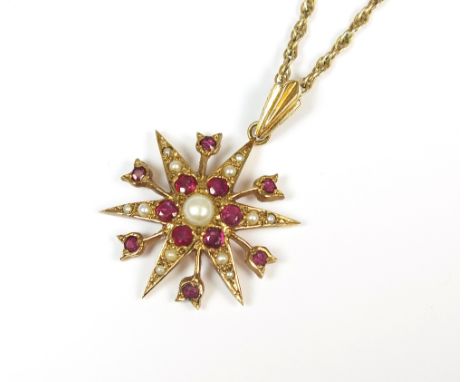 A 9ct gold seed pearl and ruby pendant, the ruby and seed pearl set star suspended from a yellow metal rope twist chain, the 