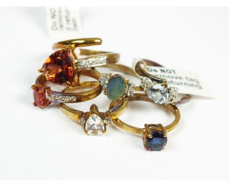 A collection of six 9ct yellow gold stone set rings to include a boulder opal and white topaz example, an aquamarine and diam