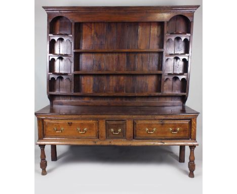 A joined oak dresser base, early 18th century, the rectangular planked top above an ogive moulding and cushion moulded square