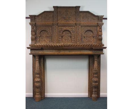 A large and ornate carved oak chimney piece, elements 17th century, the panel back centred by a shield coat of arms with rose