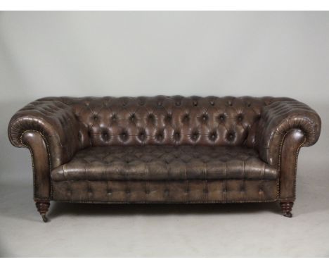 A Victorian Chesterfield settee, 19th century, the brown leather button back and seat raised on squat turned bun feet and cas