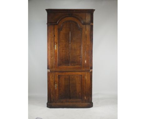 A George III oak and walnut crossbanded full height corner cabinet, circa 1800, the dentil moulded ogave cornice above an arc