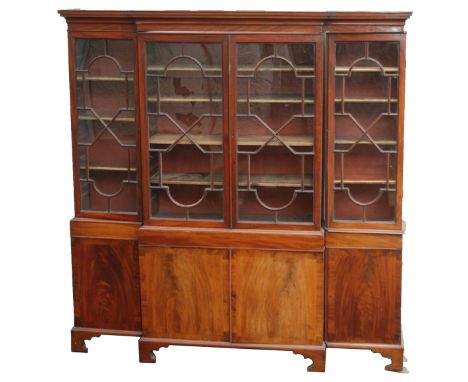 A MAHOGANY BREAKFRONT BOOKCASE the overhanging cornice above four glazed astragal doors, enclosing shelves and above four doo