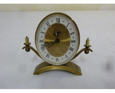 Jaccard France mantle clock, oval face, Roman numerals with flanking candle holders on a curved metal base