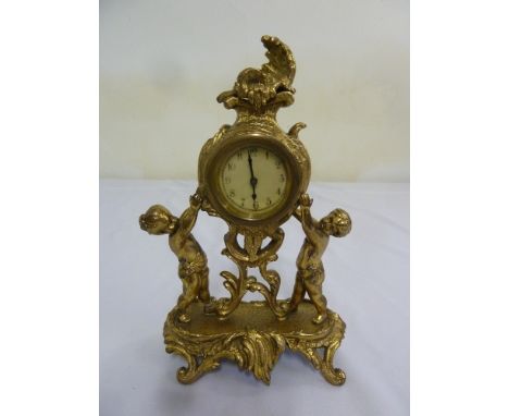 A French gilt metal Rococo style mantle clock supported by two putti on pierced leaf chased base A/F
