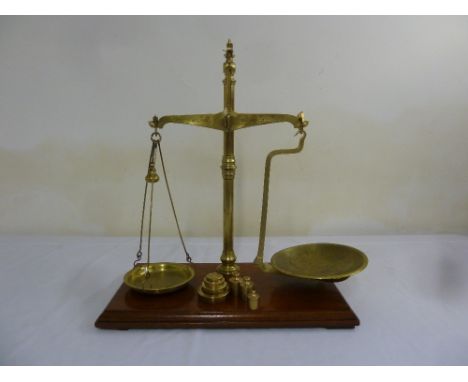 Antique brass balance scales with weights on rectangular mahogany base