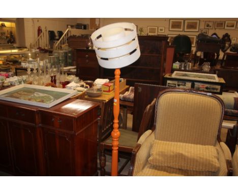 An orange painted standard lamp with shade 