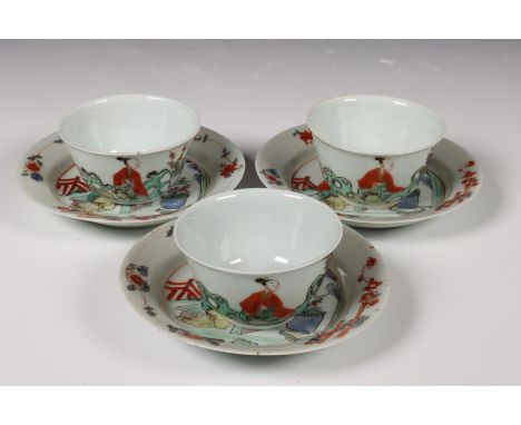 China, set van drie famille verte porseleinen koppen en schotels, vroeg 18e eeuw, elk gedecoreerd met een elegante dame in ee