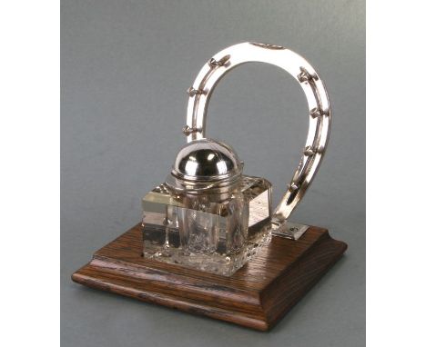 Equestrian interest.  A silver plated desk stand with horse shoe pen rest and cut glass inkwell with jockey cap cover, on an 