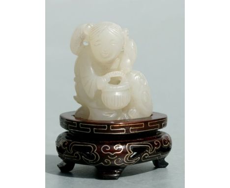A Chinese jade group depicting a seated woman with a basket beside an animal, on a hardwood stand, 4cms high.