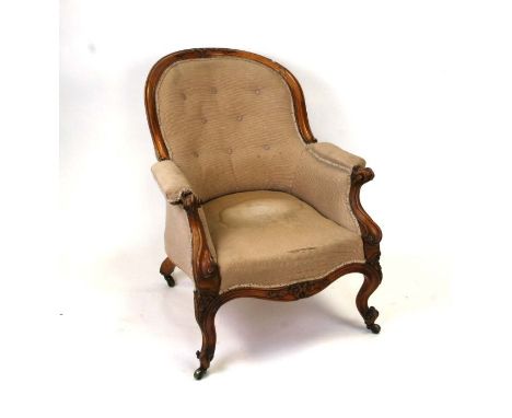 A Victorian walnut show wood upholstered armchair with button back, scroll arms and carved scroll front legs.