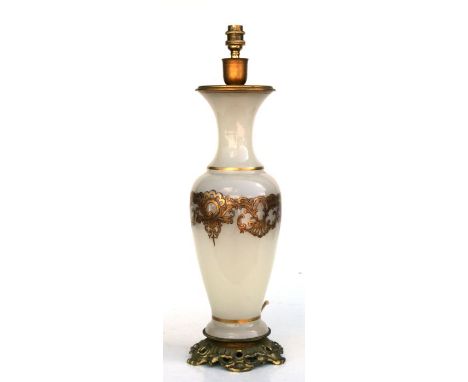 A glass table lamp with gilt metal mounts and gilded decoration, retailed by Harrods, 54cms high.