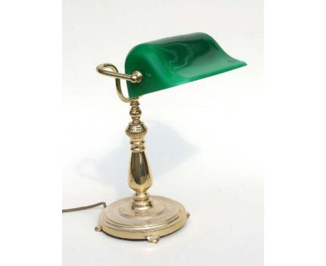 A brass bankers lamp with green glass shade.