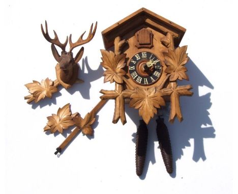 A Black Forest style cuckoo clock, the black chapter ring with Roman numerals, the case with carved oak leaf decoration and s