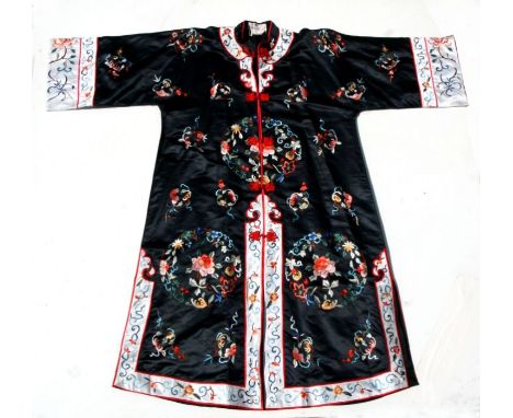 A Chinese silk embroidered jacket decorated with flowers on a black ground,  together with a similar Chinese silk embroidered
