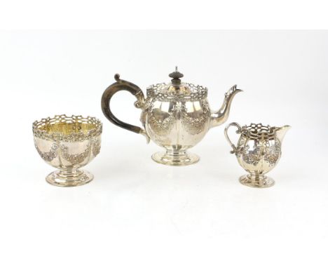 Edward VII silver three piece tea service, comprising teapot, cream jug and sugar bowl, embossed with floral swags, and galle