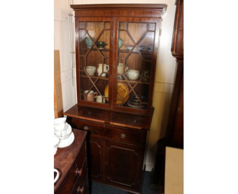 A George III style mahogany bookcase, two glazed doors above secretaire drawer with two panelled doors under, on bracket feet