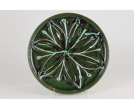 A Poole Pottery dish c1950 with raised flower detail in green, cream and brown glaze, 23cm diameter