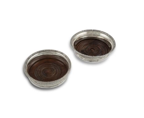 TWO SIMILAR MODERN IRISH SILVER CELTIC PATTERN DECANTER COASTERS, Dublin 1966, mark of B. Moynihan, with turned timber bases,