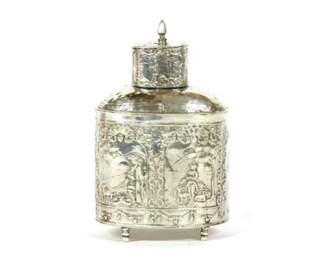 A Dutch silver tea caddy, of oval form, decorated all over with chased and engraved pastoral scenes, and on short turned feet