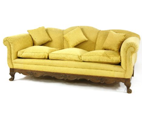 A Victorian sofa, the shaped back over three cushions, on a shaped mahogany base, carved with flower head and leaves and on b