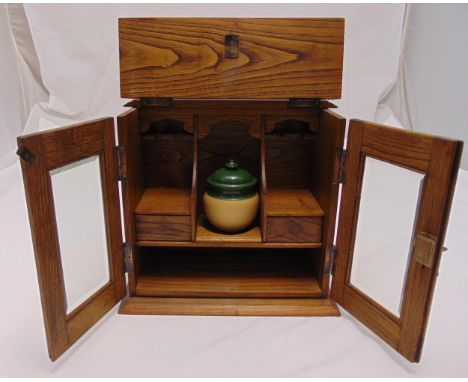 An oak rectangular smoking cabinet with glazed hinged doors revealing a pipe rack and a ceramic mixing bowl and cover