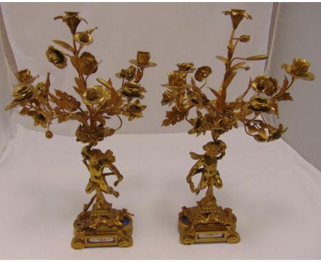 A pair of gilt metal five light candelabra, the cast angels supporting naturalistic floral arms with petal nozzles all on sha