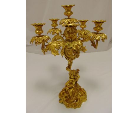 A mid 19th century Ormolu six light candelabrum with a putti supporting scrolling vine leaf arms and clusters of grapes on le