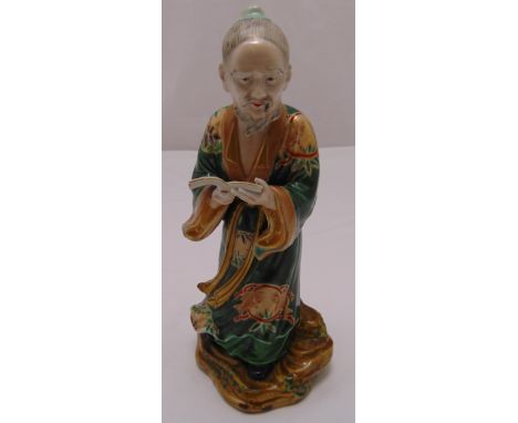 Chinese ceramic figurine of an elder holding a book on naturalistic base, 28.5cm (h)