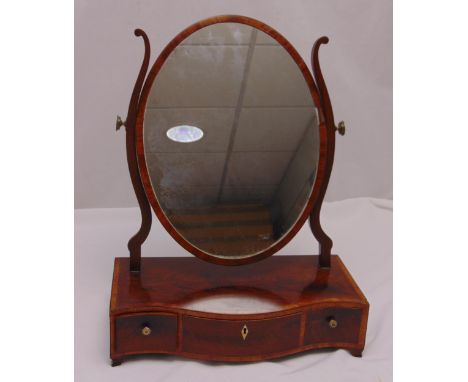 A Georgian mahogany oval dressing table mirror, the shaped rectangular plinth with three drawers on four bracket feet, 56cm (