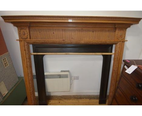 A Regency style pine chimneypiece, the overhanging shelf above a fluted central panel flanked by wreath moulded panels, the j