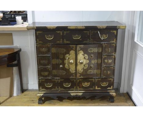 A Korean brass-mounted hardwood side cabinet, the rectangular top above three frieze drawers over a pair of cupboard doors wi